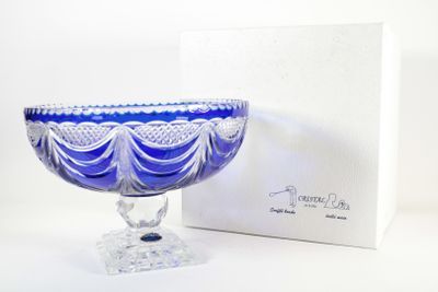 un bol en verre bleu posé sur une table à côté d'une boîte blanche