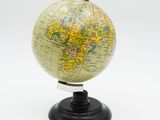 un petit globe posé sur un socle, sur une surface blanche