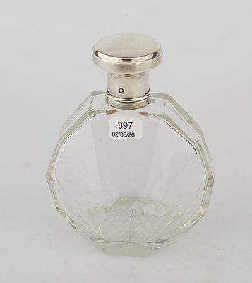 a glass bottle with a silver lid on a white surface