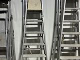 Plusieurs échelles sont alignées contre un mur dans un entrepôt.