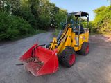 un petit tracteur jaune garé sur le bord de la route