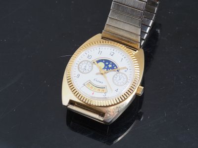 an image of a gold and silver watch on a black surface