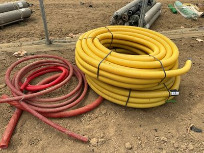 des tuyaux jaunes et rouges posés par terre à côté d'un tas de tuyaux