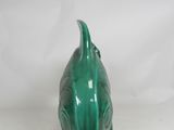 a small green fish figurine sitting on a white surface