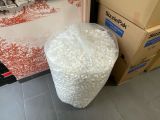 a large bag of plastic beads sitting on the floor next to a pile of boxes