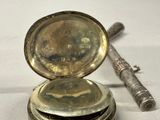 a silver pocket watch sitting on top of a stack of coins