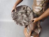 a bronze statue of a woman holding a plate