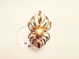 a close up of a gold spider brooch on a white surface