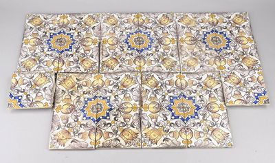 quatre carreaux carrés ornés de motifs dorés et bleus, posés sur une table