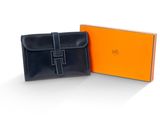 une boîte orange et noire contenant un sac à main noir et un portefeuille noir
