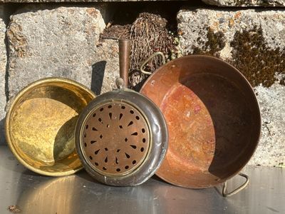 trois casseroles posées sur une table près d'un mur de pierre