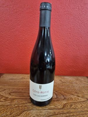 La bouteille de vin est posée sur la table, devant un mur rouge.