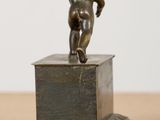 a small bronze statue of a boy on a pedestal