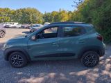 a green car parked in a parking lot next to a forest
