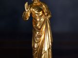 gold statue of a woman holding a candle on a wooden table