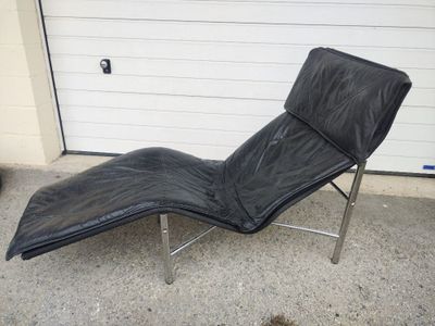 an image of a black leather chaise lounger in front of a garage