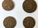 four bronze medals depicting a city, a river, and a bridge