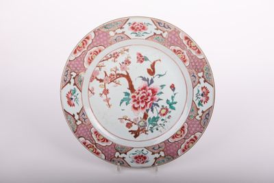a plate with flowers and birds on it on a stand