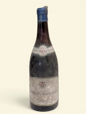 une vieille bouteille de vin posée sur une surface blanche
