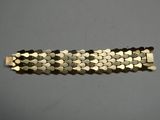 un gros plan d'un bracelet en métal posé sur une surface grise