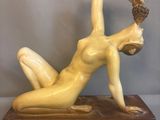 statue of a woman laying on her stomach on a wooden base