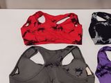 three women ' s sports bra tops on a table with a cell phone