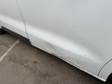 the side of a white car with a dent in it ' s side