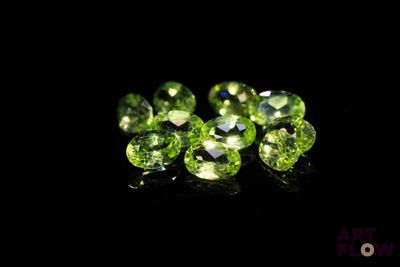 a close up of a bunch of green gems on a black surface