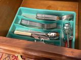 a person holding a tray with silverware in it