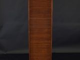a tall wooden cabinet with shutters on top of it