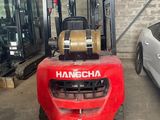 a red forklift parked in a garage next to a white car