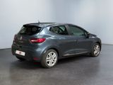 a grey car is parked in a room with a white wall