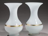 une paire de vases blancs et dorés posés sur une surface grise