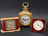 two clocks and a picture frame on a table with a black background