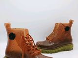 une paire de bottes marron à semelles vertes sur un fond blanc