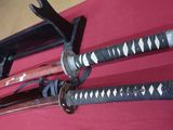 two samurai swords on display on a red table