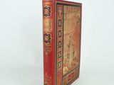 un vieux livre à la couverture rouge posé sur une surface blanche
