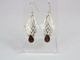 a pair of silver and garnetite earrings on a clear display case