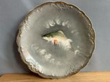 a plate with a fish painted on it sitting on a table