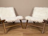 une paire de fauteuils en peau de mouton blanche devant un mur beige