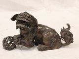 bronze figurine of a dog laying down on a white surface
