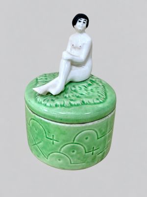 a small green box with a figurine of a woman sitting on it