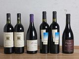 several bottles of wine are lined up on a wooden table