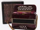 an image of a red accordion sitting next to a black box