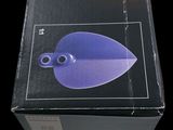 packaging of a purple plastic object in a box on a black background