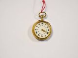 a small gold pocket watch hanging from a red string