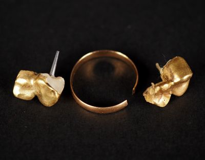 un gros plan d'une bague et d'une boucle d'oreille en or sur une surface noire