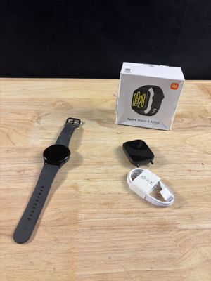 Une Apple Watch est posée sur une table en bois, à côté d'une boîte et d'un chargeur