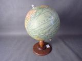 un petit globe terrestre posé sur un socle en bois, sur fond gris