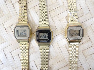 two watches are sitting side by side on a woven surface